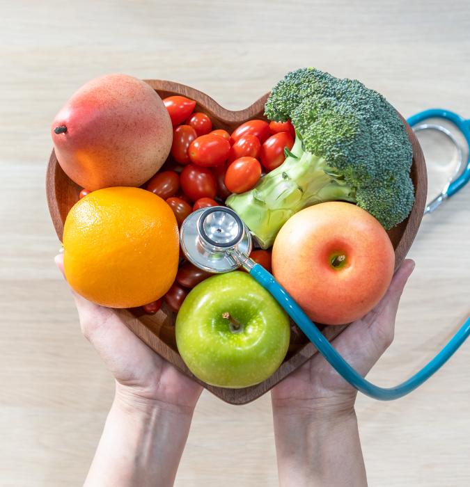 A Caregiver holding a heart-shaped bowl full of healthy food options.