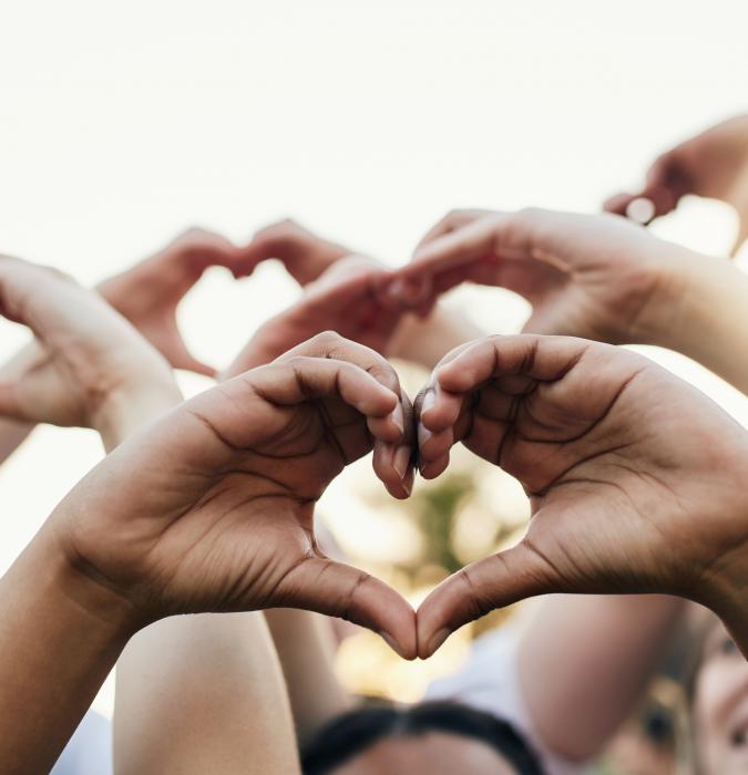 Group of hands creating a heart shape. 