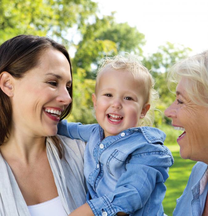 Mother holding her baby with grandmother smiling outdoors