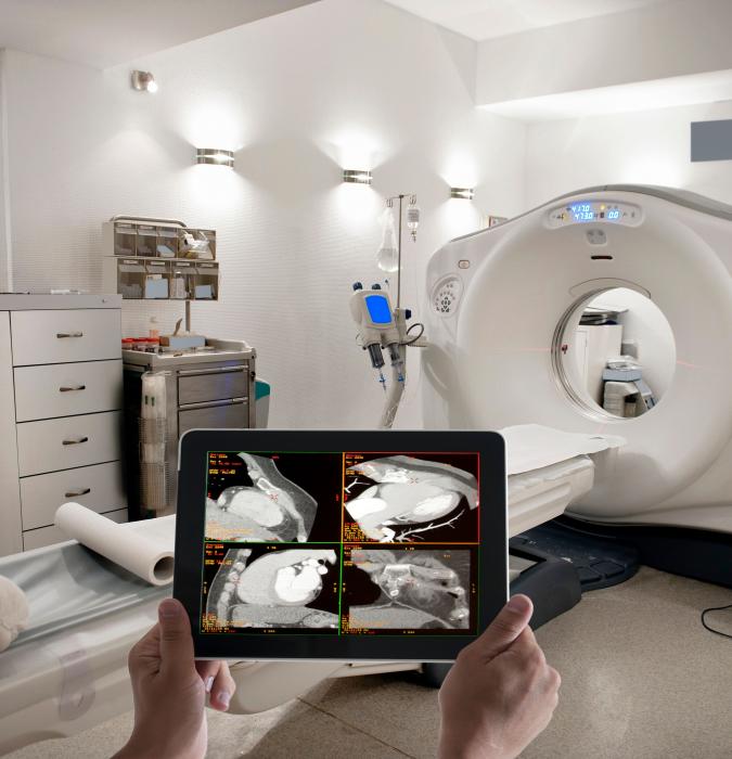 Person holding scans in medical room with radiology equipment