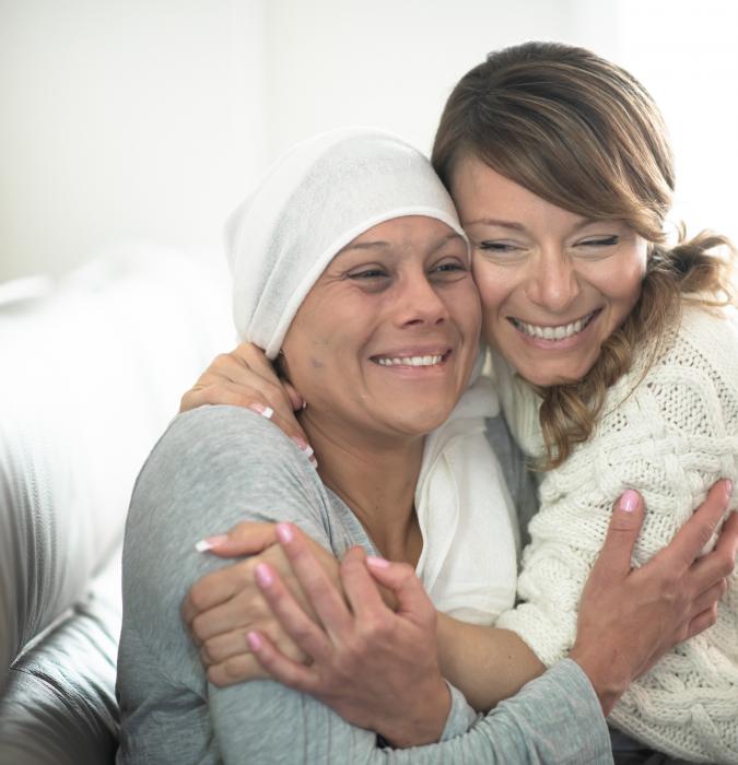 Oncology patient and friend hugging and smiling