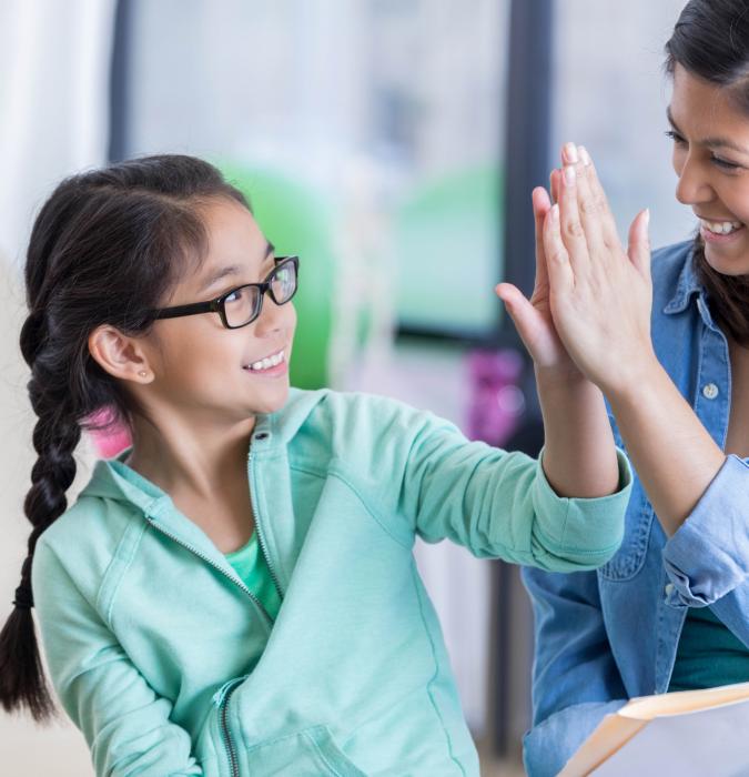 A girl with glasses high-fives her counselor. 