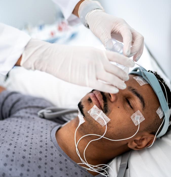 Doctor preparing patient in bed for polysomnography (sleep study) 