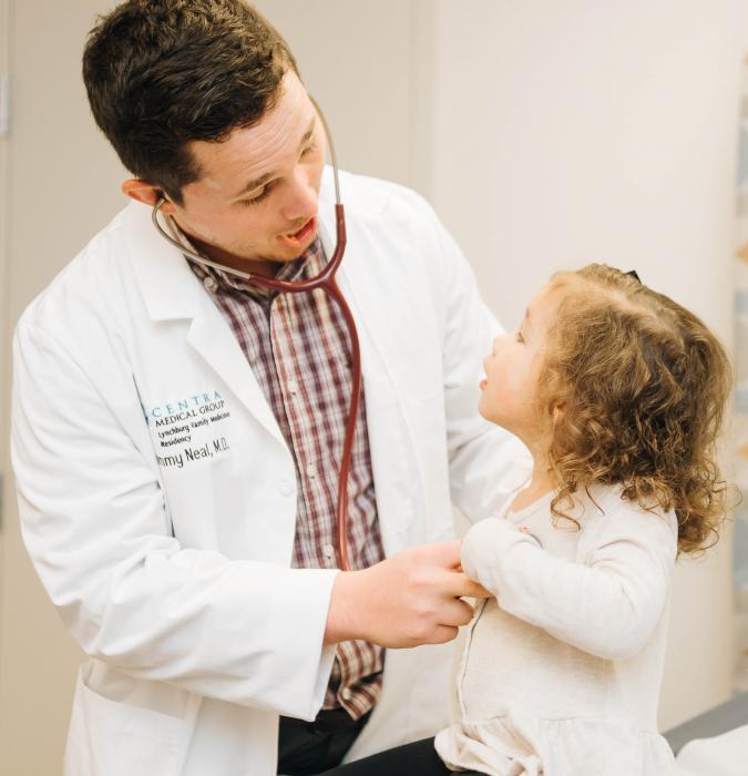 Thomas Neal, MD, cares for a young girl during her checkup.  